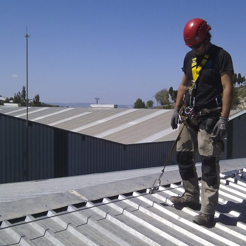 Trabajador utilizando línea de vida con carro de traslación en nave industrial