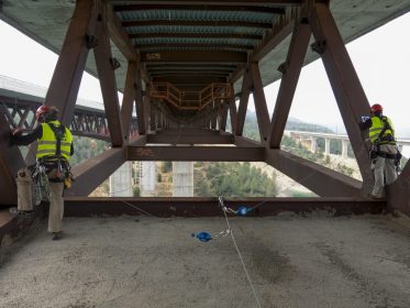 Trabajadores verticales instalando línea de vida en puente metálico